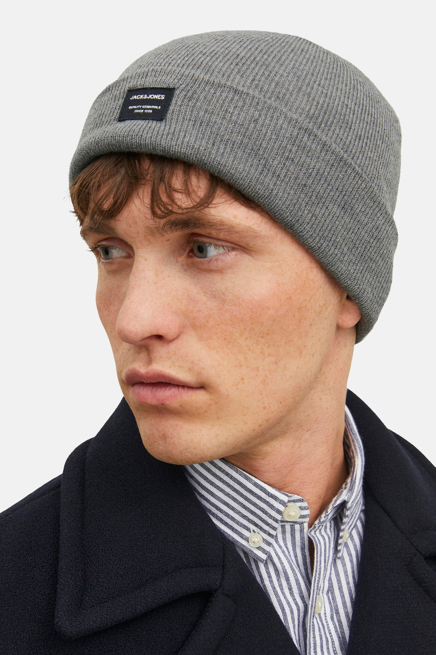 Bonnet gris en tricot de ACCESSORIES BY JACK & JONES, porté avec une chemise rayée et une veste bleu marine.