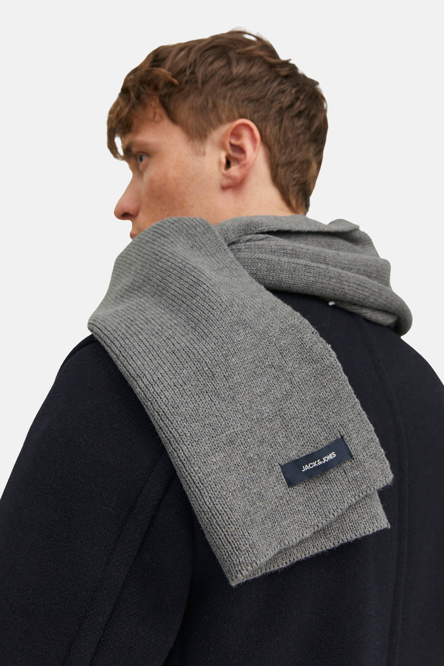 Écharpe grise en tricot par ACCESSORIES BY JACK & JONES, portée avec un manteau sombre.