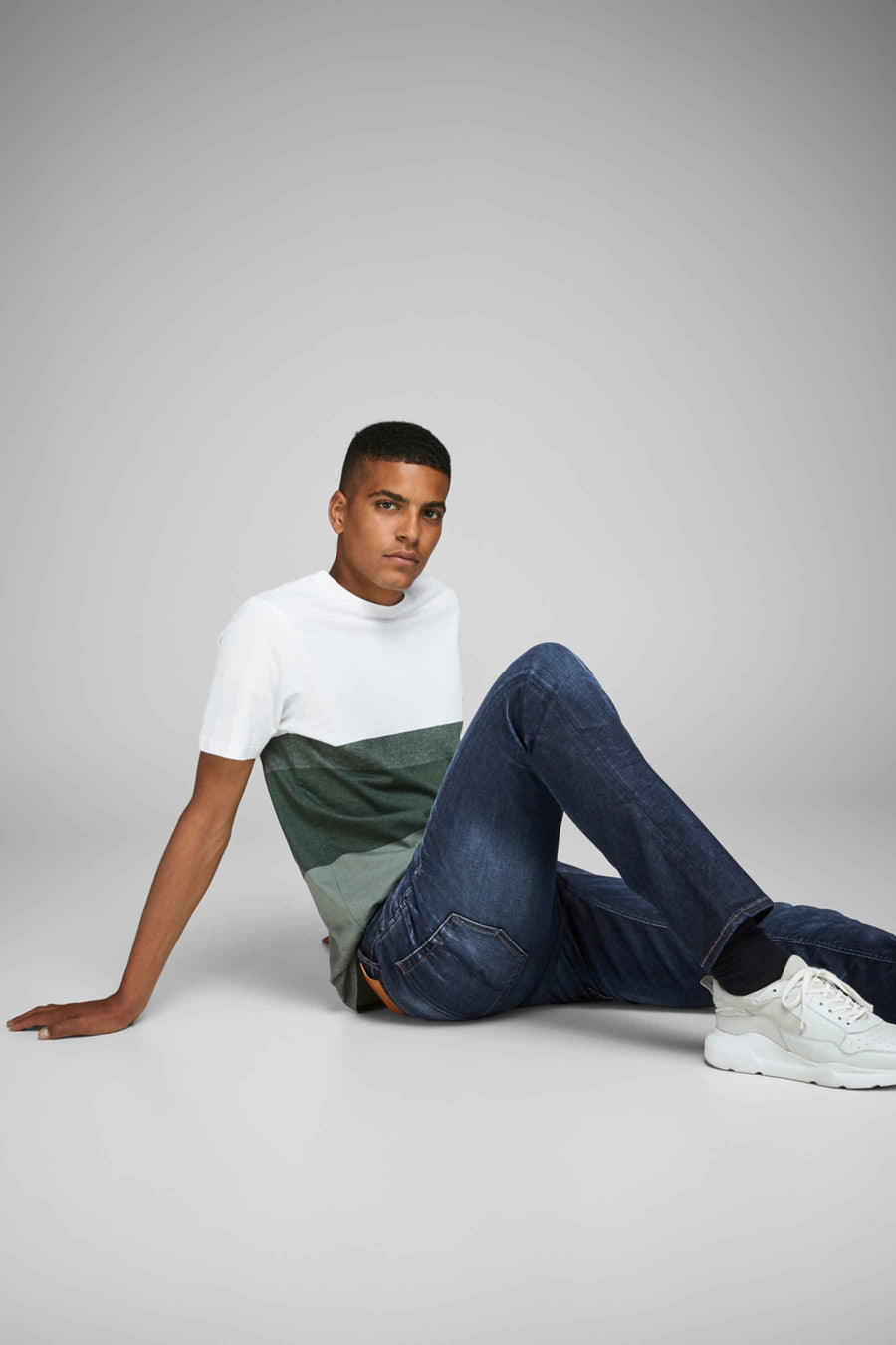 Donkerblauwe slim fit jeans van JACK & JONES JEANS INTELLIGENCE, gedragen met een gestreept T-shirt en witte sneakers.