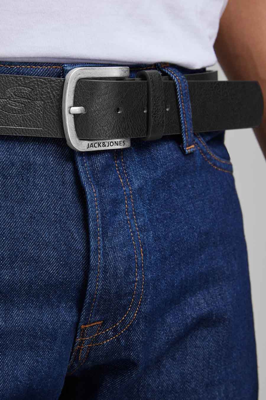 Ceinture noire en cuir synthétique de ACCESSORIES BY JACK & JONES, avec boucle rectangulaire argentée sur un jean bleu foncé.
