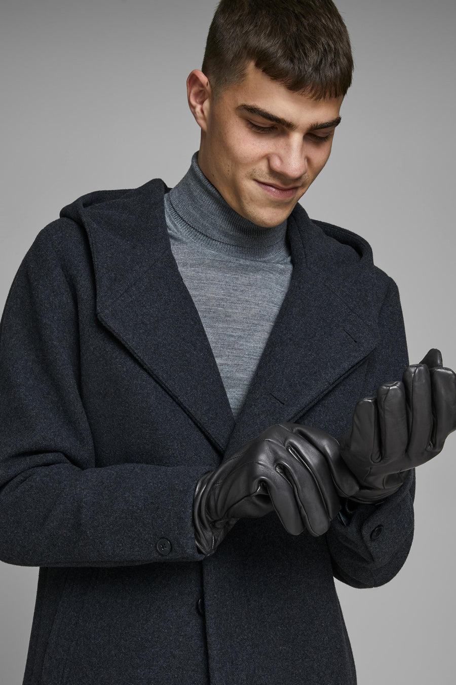 Gants noirs en cuir par ACCESSORIES BY JACK & JONES, portés avec un manteau à capuche et un col roulé gris.
