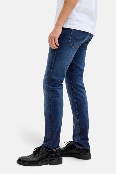 Mid blue slim-fit denim jeans by Glenn, side view with subtle fading, worn with white t-shirt and black brogues