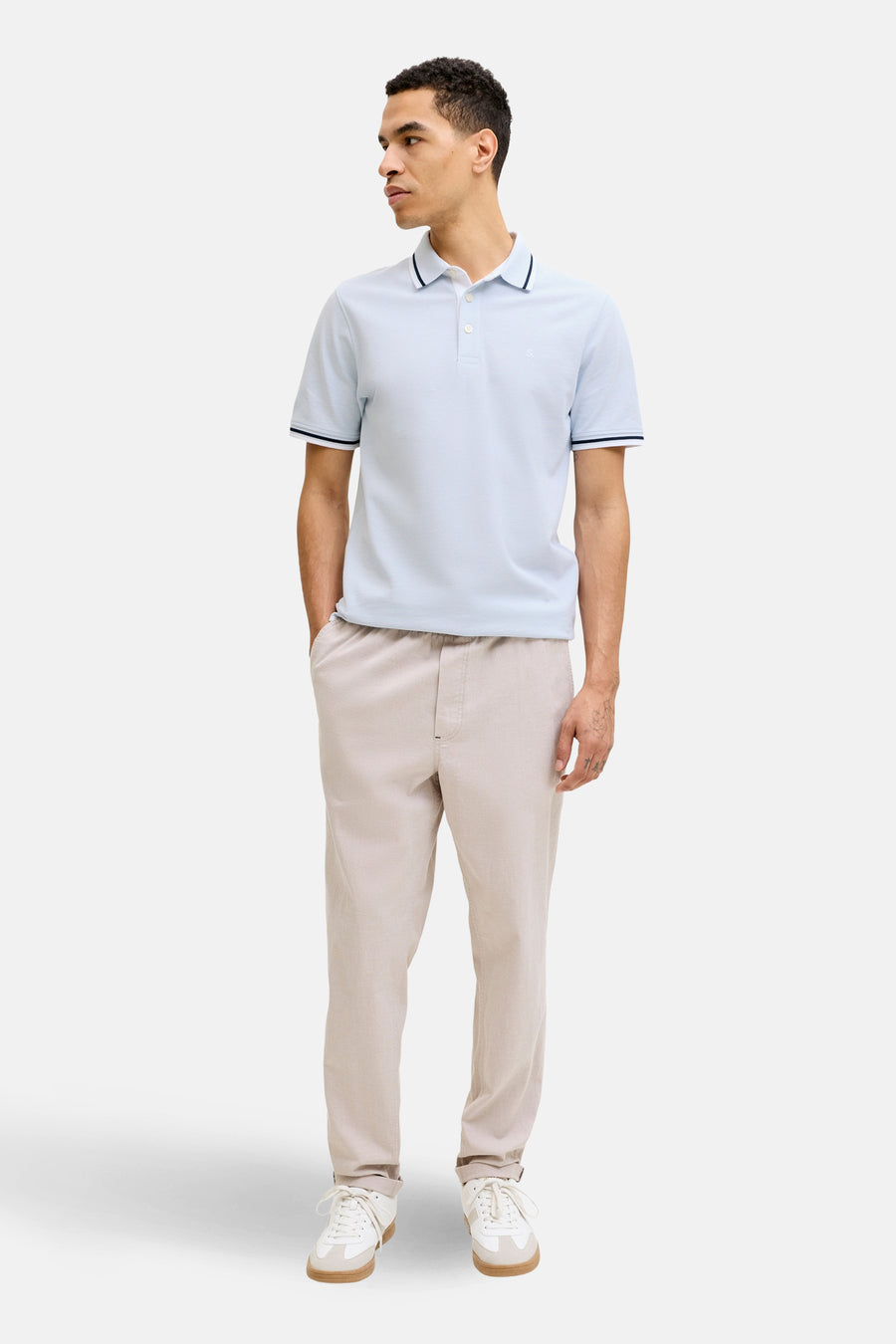 Polo bleu à manches courtes de PREMIUM by JACK & JONES, avec des bordures marine, porté avec un pantalon beige et des baskets blanches.