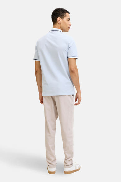Polo bleu à manches courtes de PREMIUM by JACK & JONES, vu de dos, porté avec un pantalon beige.
