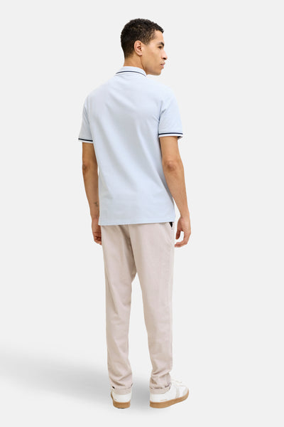 Polo bleu à manches courtes de PREMIUM by JACK & JONES, vu de dos, porté avec un pantalon beige.
