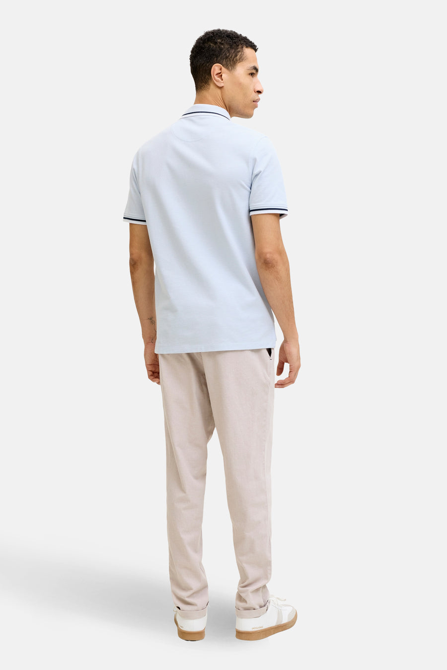 Polo bleu à manches courtes de PREMIUM by JACK & JONES, vu de dos, porté avec un pantalon beige.
