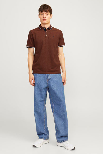 Polo à manches courtes brun de PREMIUM BY JACK & JONES, avec bordure blanche, porté avec un jean ample et des baskets blanches.