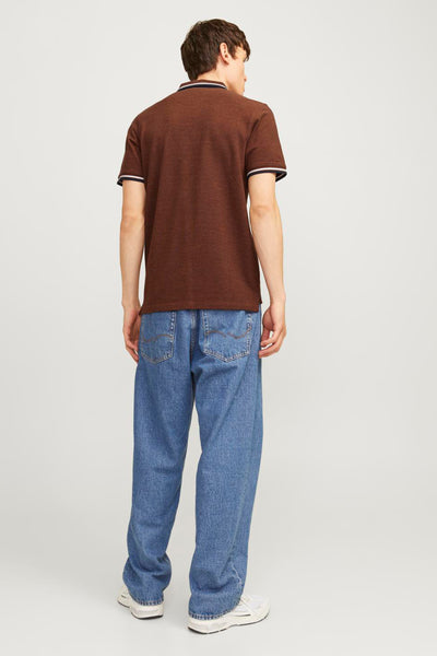 Polo marron à manches courtes de PREMIUM BY JACK & JONES, porté avec un jean bleu ample et des baskets blanches.