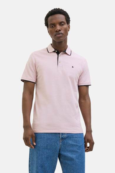 Polo rose à manches courtes de PREMIUM by JACK & JONES, avec bordure noire au col, porté avec un jean bleu.
