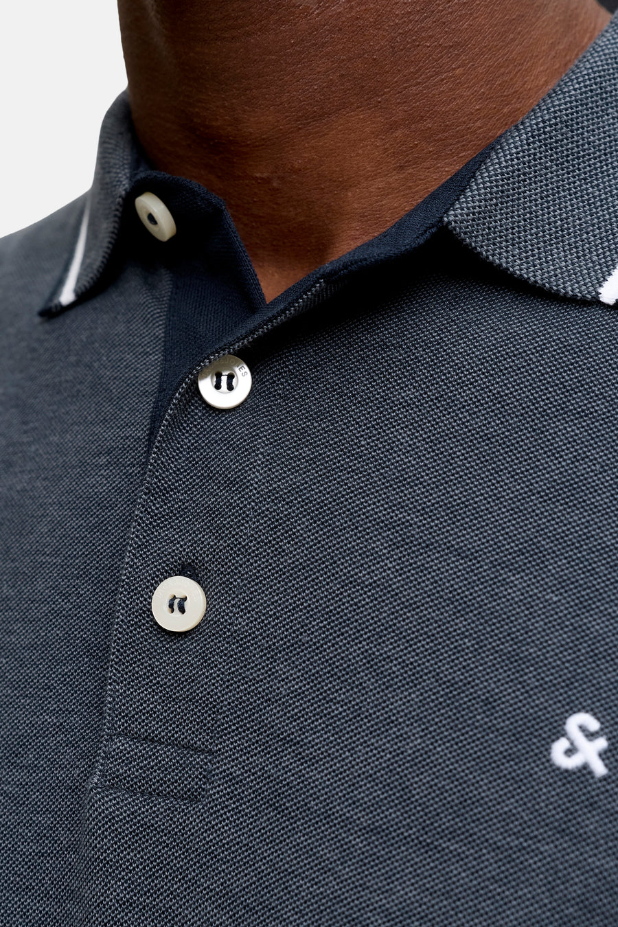 Navy blue piqué polo shirt by Fred Perry, featuring white contrast collar trim and embroidered logo on chest, close-up front view