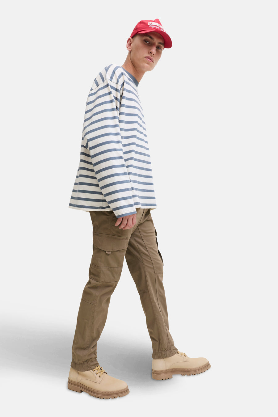 Pantalon cargo brun de JACK & JONES JEANS INTELLIGENCE, porté avec un t-shirt rayé et une casquette rouge.