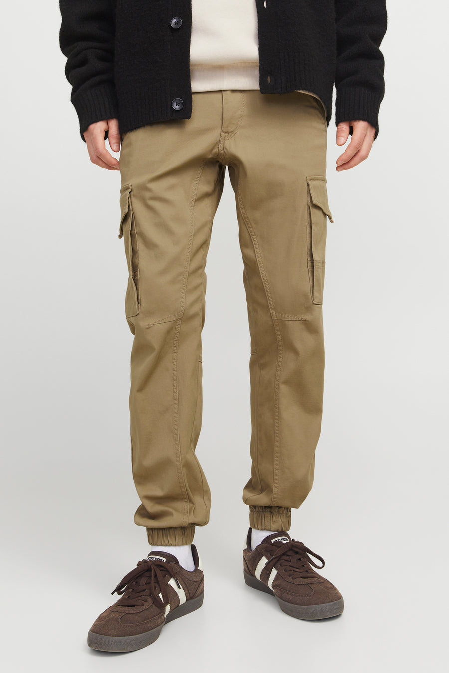 Pantalon cargo kaki de JACK & JONES JEANS INTELLIGENCE, porté avec des chaussures de sport marron et un cardigan noir.