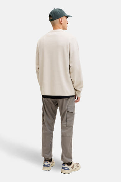 Bruine cargobroek van JACK & JONES JEANS INTELLIGENCE met zijzakken, gedragen met een beige trui en sportschoenen.