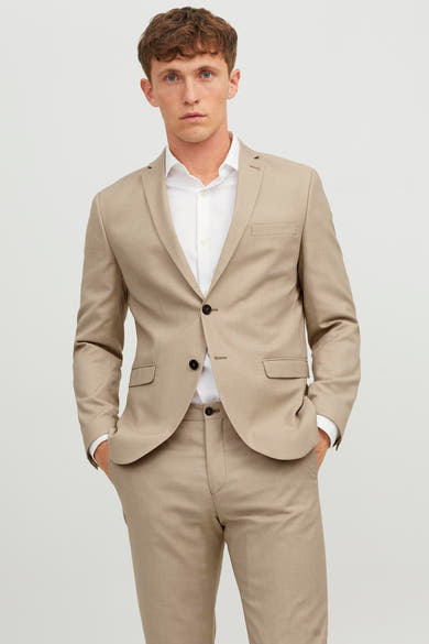 Beige blazer PREMIUM van JACK & JONES, gedragen met een wit overhemd, met de handen in de zakken.