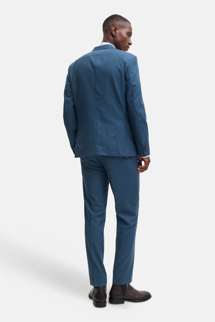 Blue tailored suit pants by JACK & JONES, shown from back view with matching blazer, slim fit, smooth texture, and dark brown boots.