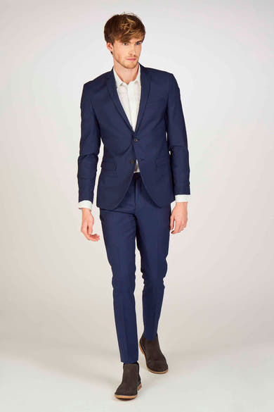 Blauwe kostuumbroek van PREMIUM by JACK & JONES, gedragen met een wit overhemd en bruine enkellaarsjes.