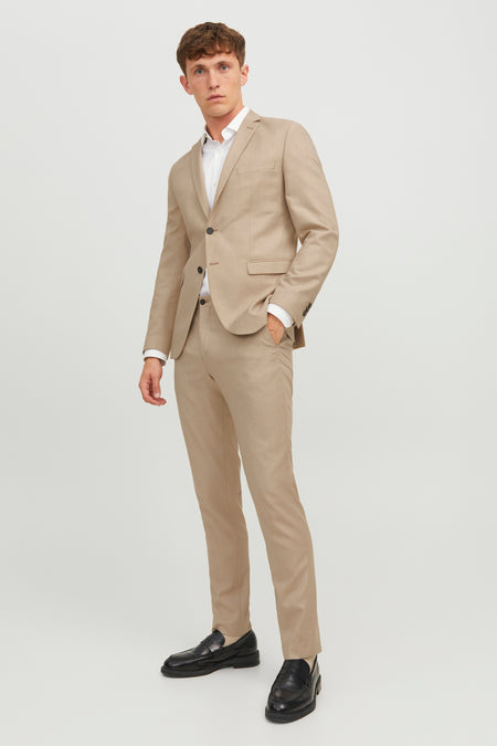 Pantalon de costume beige par PREMIUM BY JACK & JONES, coupe ajustée, porté avec veste assortie et chaussures noires.
