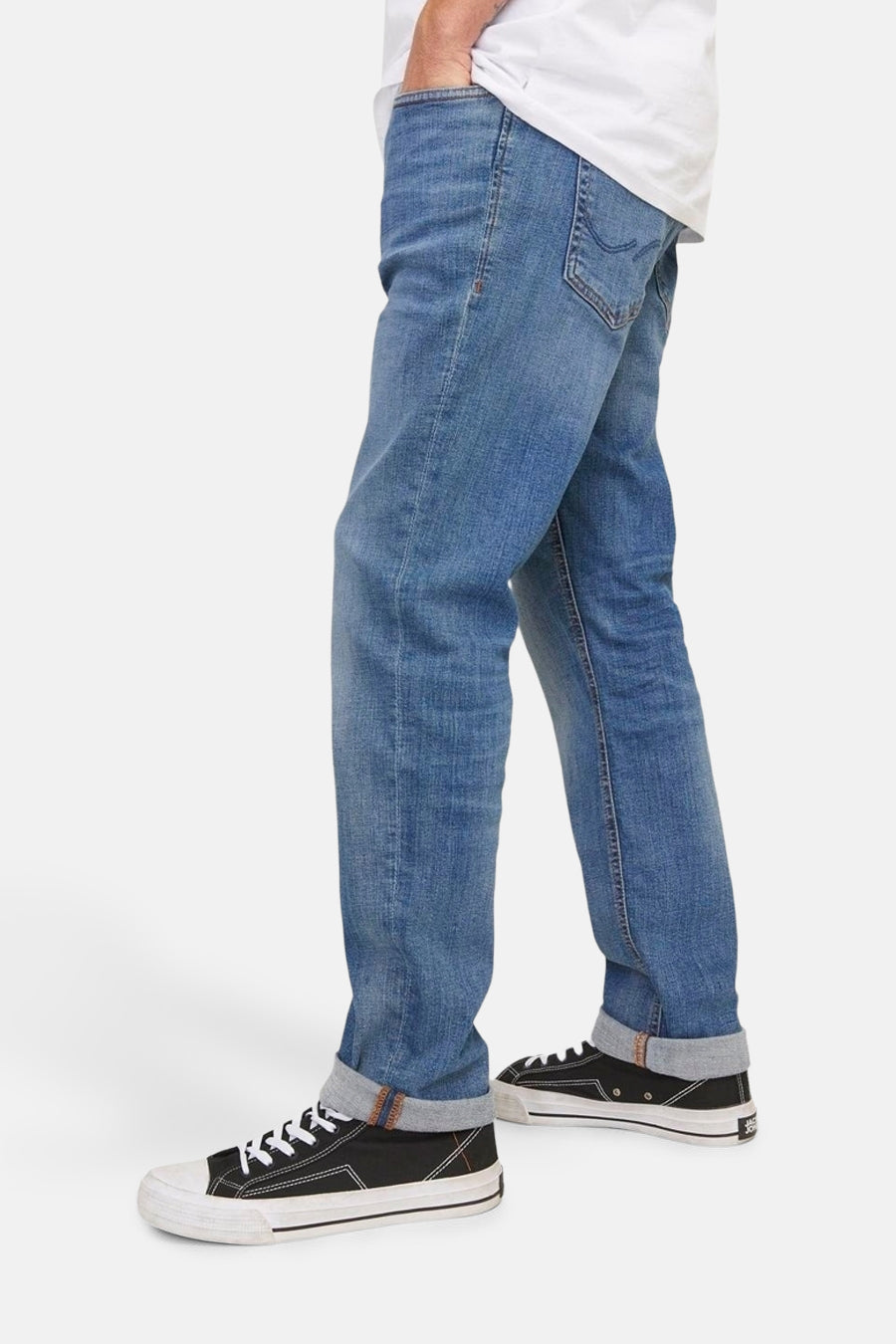 Slim jeans in medium blue denim van JACK & JONES, met omslag en zwarte sneakers met witte zolen.