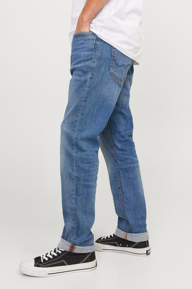 Middelblauwe slim fit jeans van JACK & JONES JEANS INTELLIGENCE, gedragen met een wit T-shirt en zwarte canvas schoenen.