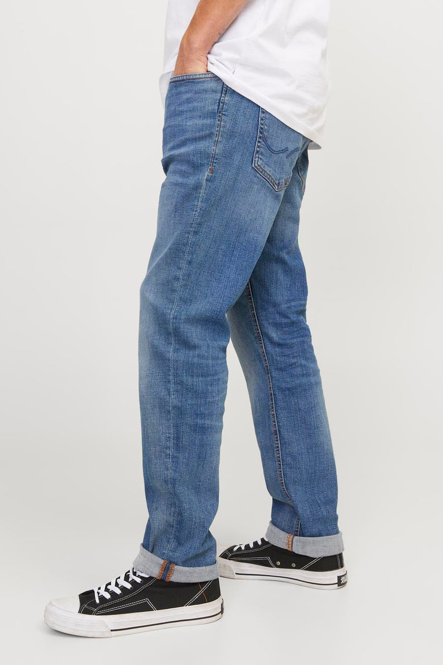 Middelblauwe slim fit jeans van JACK & JONES JEANS INTELLIGENCE, gedragen met een wit T-shirt en zwarte canvas schoenen.