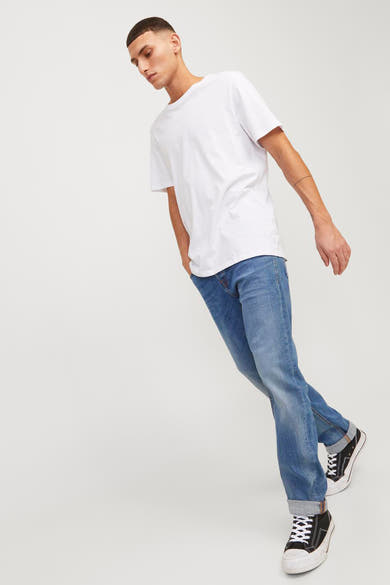 Middelblauwe slim fit jeans van JACK & JONES JEANS INTELLIGENCE, gedragen met een wit T-shirt en zwart-witte hoge sneakers.