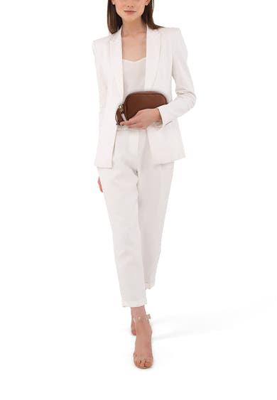 Sac à bandoulière brun d'Access®, porté par une femme en tailleur pantalon blanc et escarpins transparents.