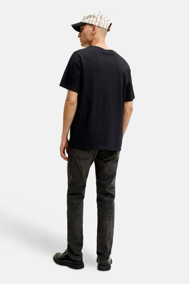 Zwart T-shirt met korte mouwen van JACK & JONES gedragen op de rug door een man met een spijkerbroek en een gestreepte pet.
