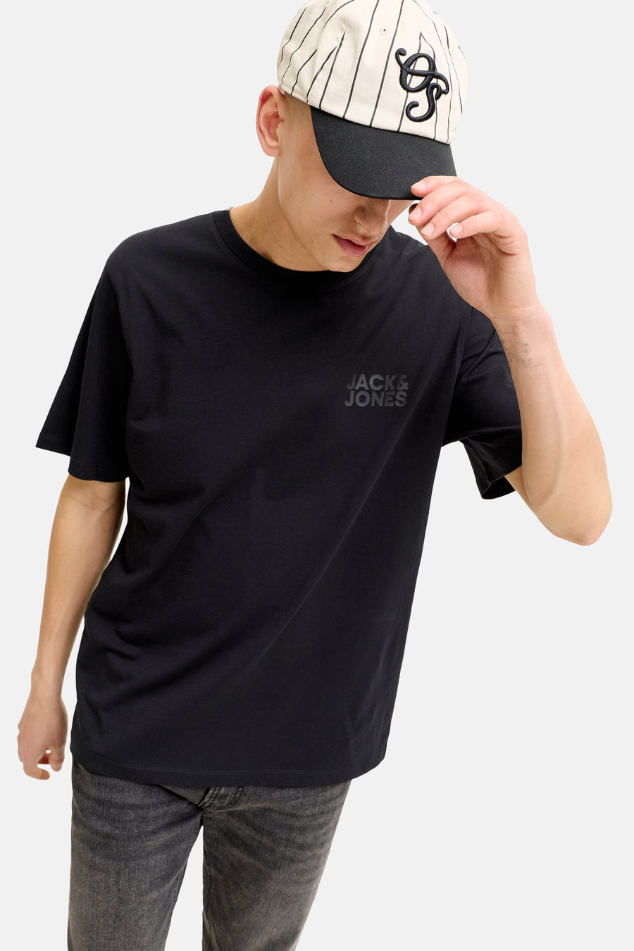 T-shirt à manches courtes noir de JACK & JONES avec logo tonal, porté par un modèle en casquette à rayures et jean foncé.