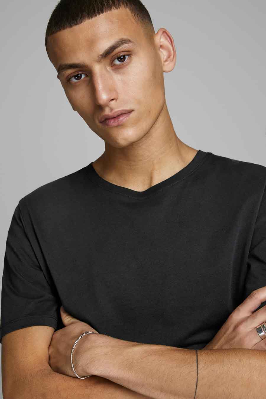 T-shirt noir de JACK & JONES, porté par un homme avec un bracelet argenté et une bague.
