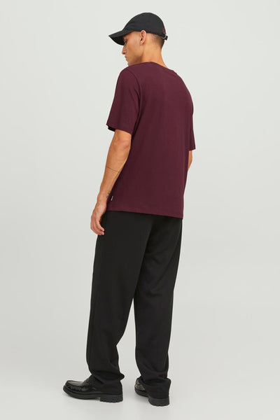 Bordeauxrode T-shirt met korte mouwen van JACK & JONES, gedragen met een zwarte broek en een zwarte pet.