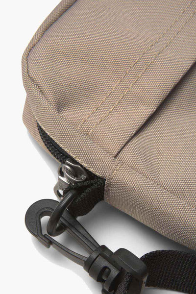Beige canvas crossbody bag with black zipper and adjustable strap, side view close-up