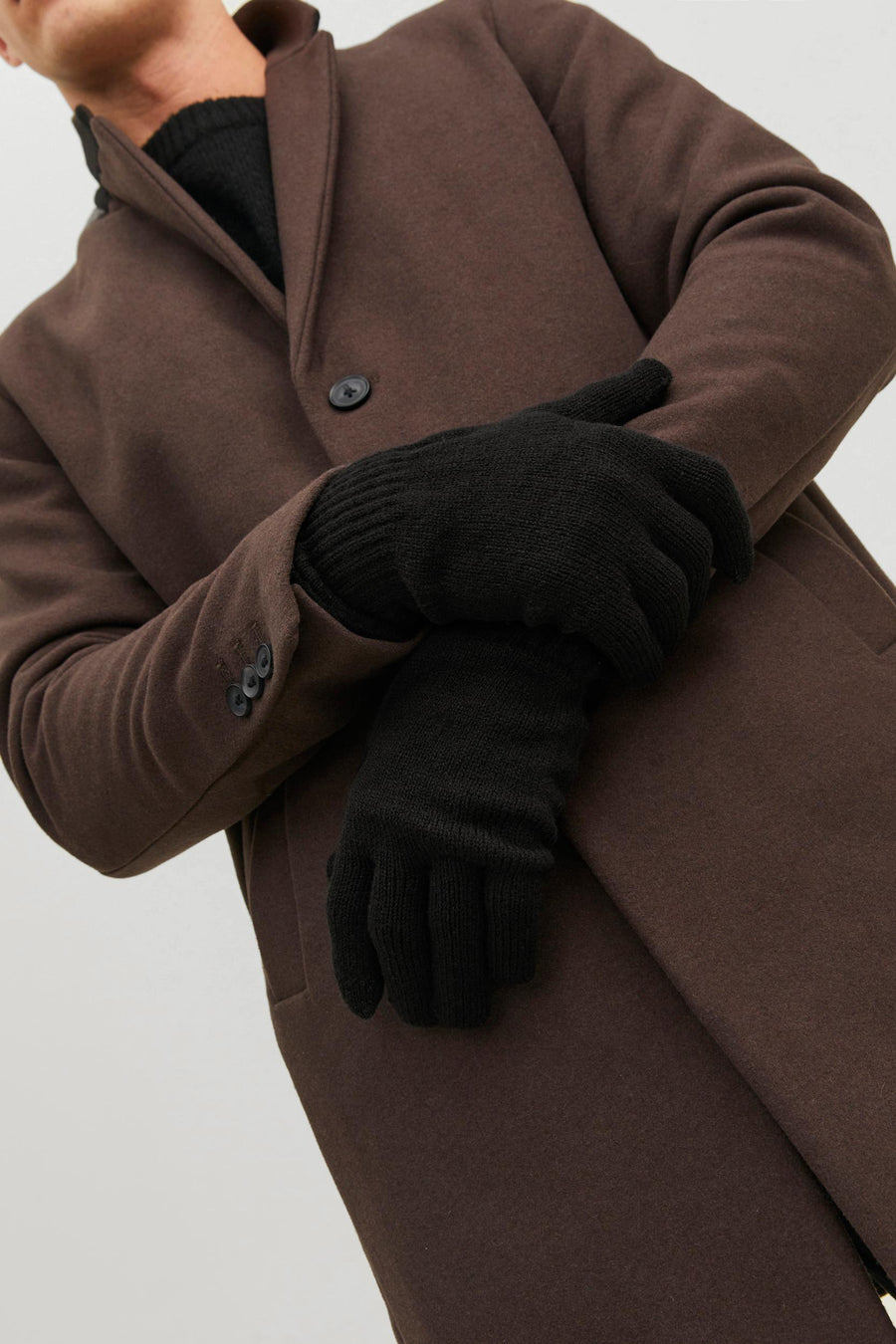 Gants noirs par ACCESSORIES BY JACK & JONES portés avec un manteau marron, mains croisées.