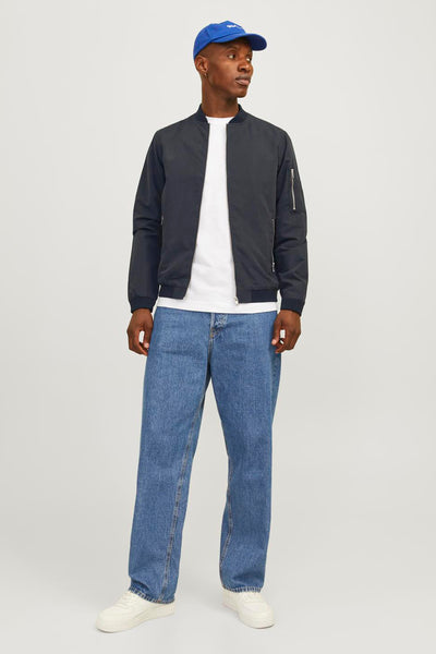 Veste courte noire de PREMIUM BLUE BY JACK & JONES, avec fermeture éclair et détails de poche, portée avec un t-shirt blanc et un jean bleu ample.