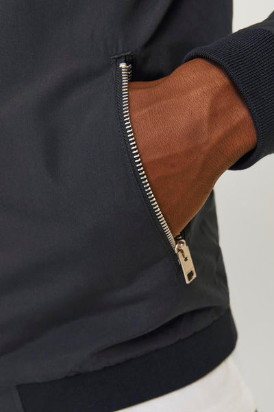 Korte jas van PREMIUM BLUE BY JACK & JONES, met een zilveren knop en een hand in de zak.