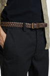 Gevlochten bruine riem van ACCESSORIES BY JACK & JONES over zwarte textuur broek, casual outfit detail.
