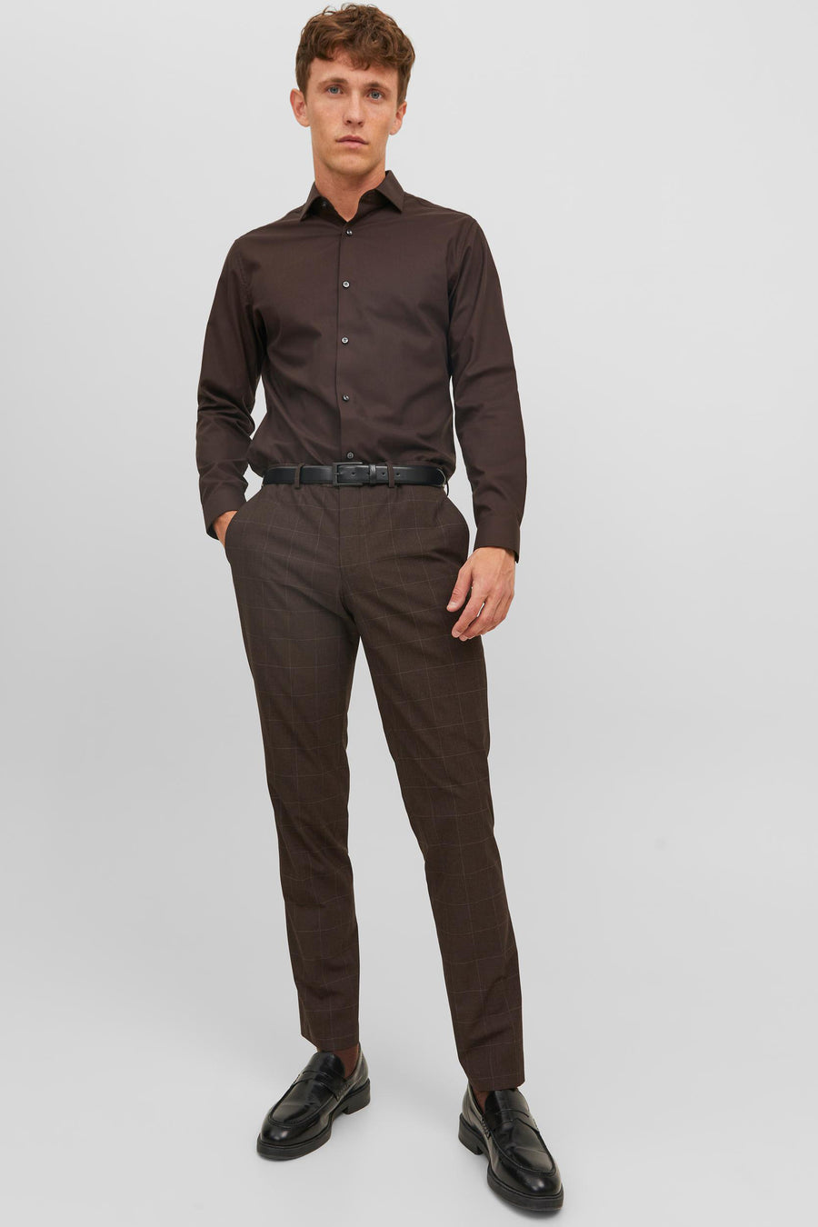 Pantalon de costume marron à carreaux par PREMIUM by JACK & JONES, porté avec une chemise brune et des mocassins noirs.
