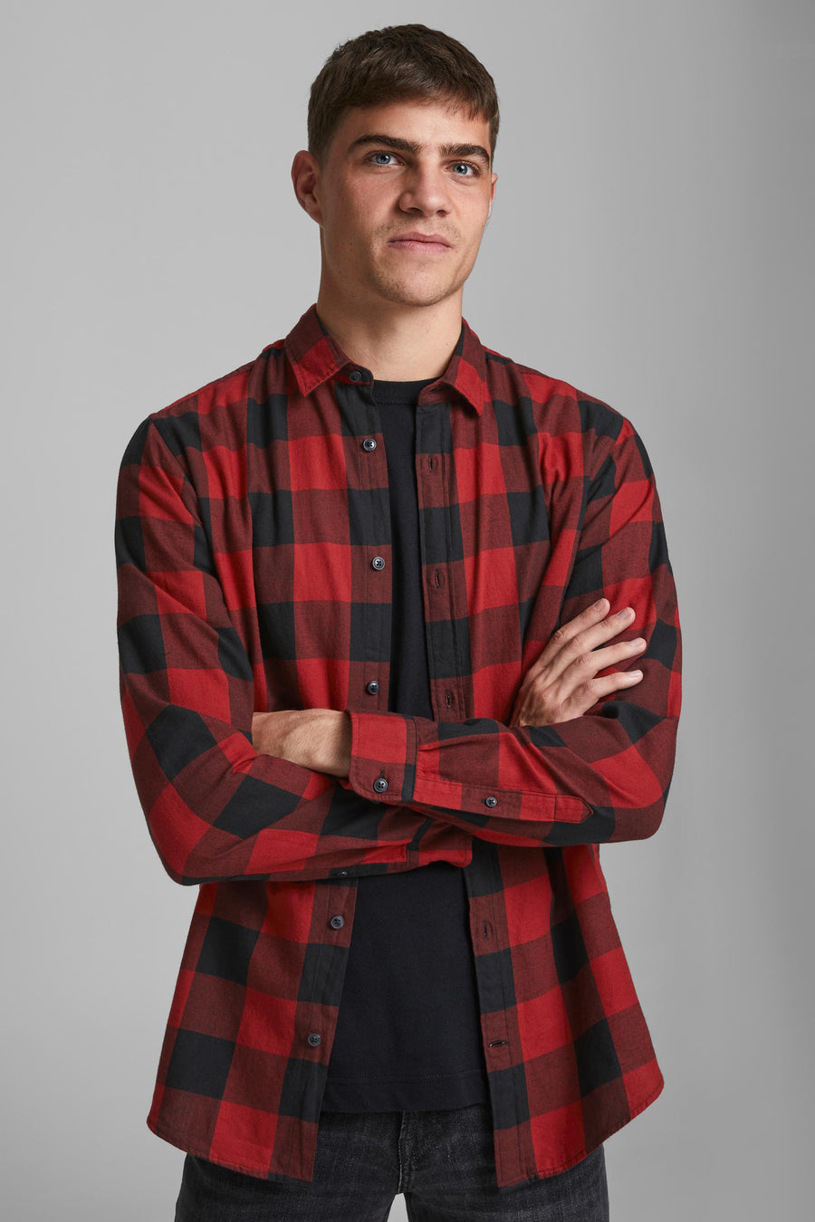 Rood geruit overhemd met lange mouwen van JACK & JONES, gedragen over een zwart T-shirt, armen over elkaar.