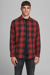 Rood en zwart geruit overhemd met lange mouwen van JACK & JONES, gedragen over een zwart T-shirt en een donkere spijkerbroek.