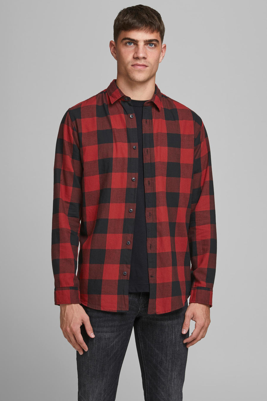 Rood en zwart geruit overhemd met lange mouwen van JACK & JONES, gedragen over een zwart T-shirt en een donkere spijkerbroek.