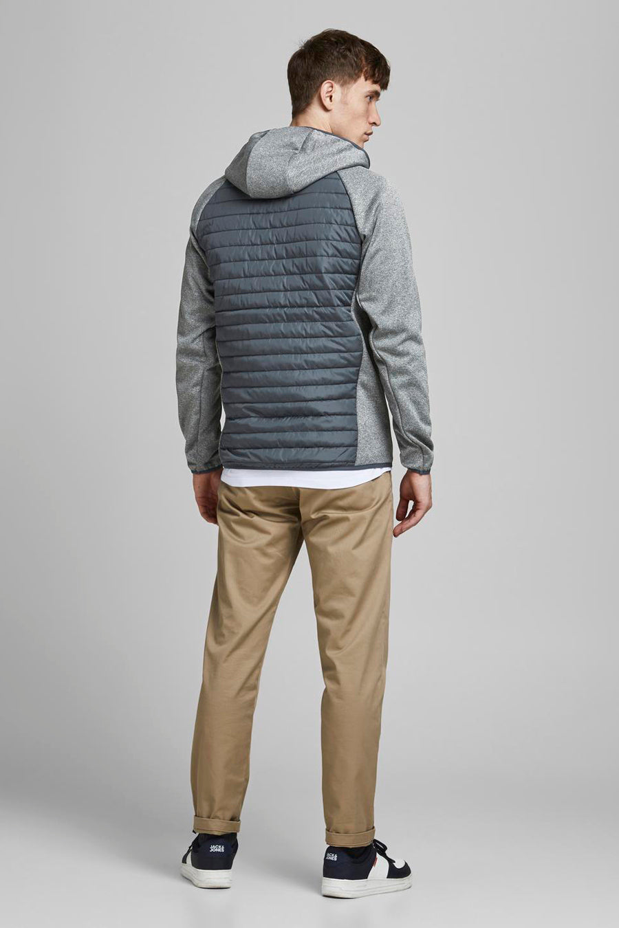 Grijze waterdichte jas van JACK & JONES, met capuchon en gewatteerd rugpaneel, gedragen met een kaki broek.