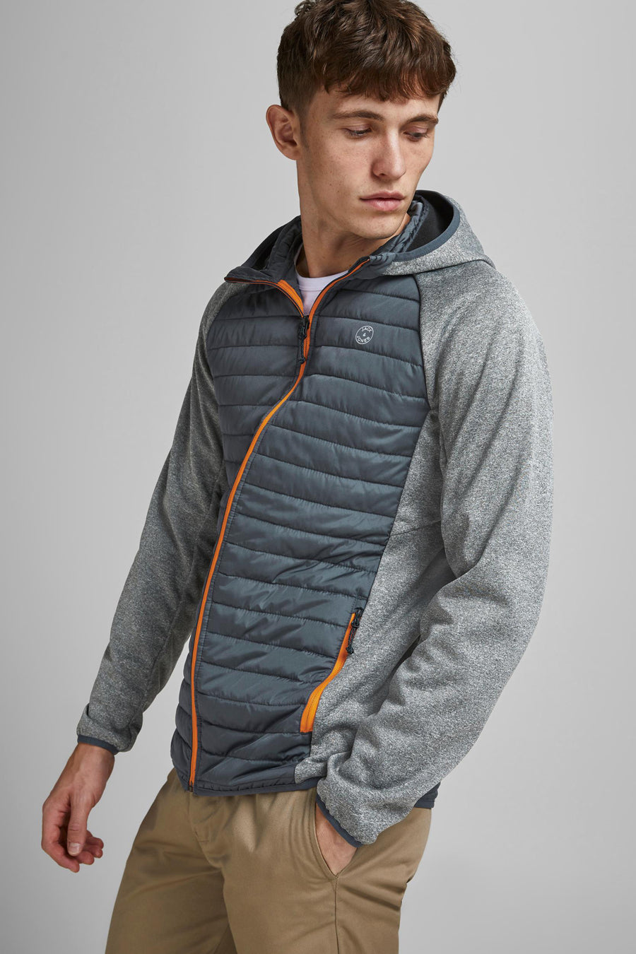 Grijze regenjas van JACK & JONES met capuchon en gewatteerde details, gedragen met een kaki broek.