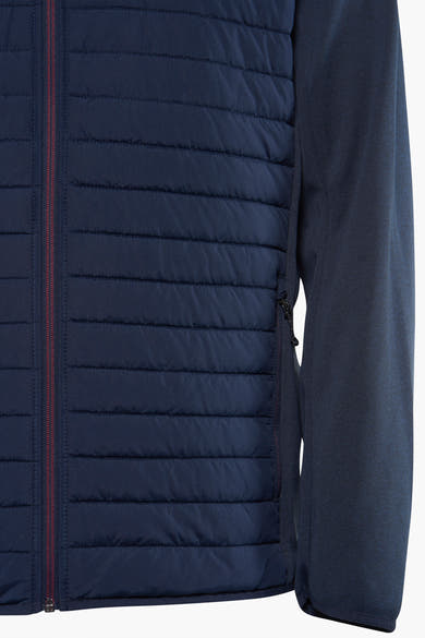 Korte blauwe jas van JACK & JONES, met een gewatteerde textuur aan de voorkant en een bordeauxrode ritssluiting.