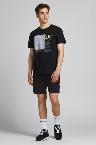 Korte spijkerbroek van JACK & JONES JEANS INTELLIGENCE, gedragen met een T-shirt met print, witte sokken en zwarte sneakers.