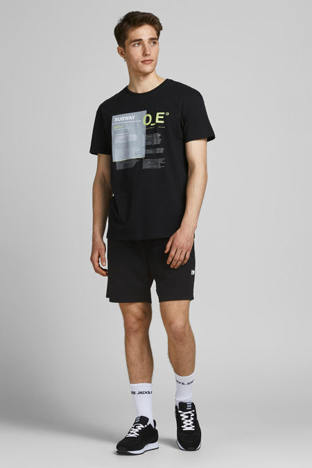 Korte spijkerbroek van JACK & JONES JEANS INTELLIGENCE, gedragen met een T-shirt met print, witte sokken en zwarte sneakers.