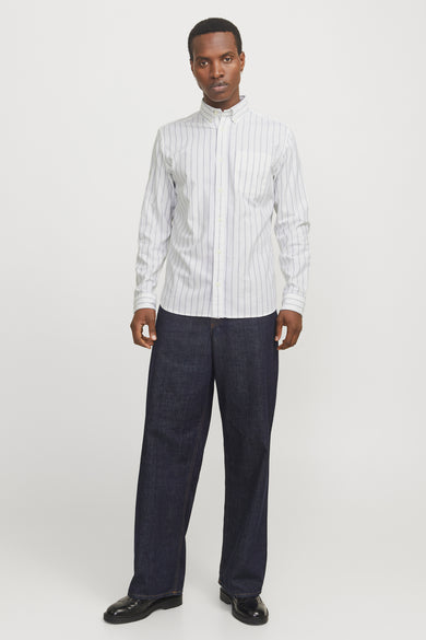 Chemise à manches longues blanche à rayures fines de PREMIUM by JACK & JONES, portée avec un pantalon ample.
