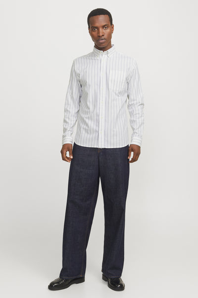 Chemise à manches longues blanche à rayures fines de PREMIUM by JACK & JONES, portée avec un pantalon ample.
