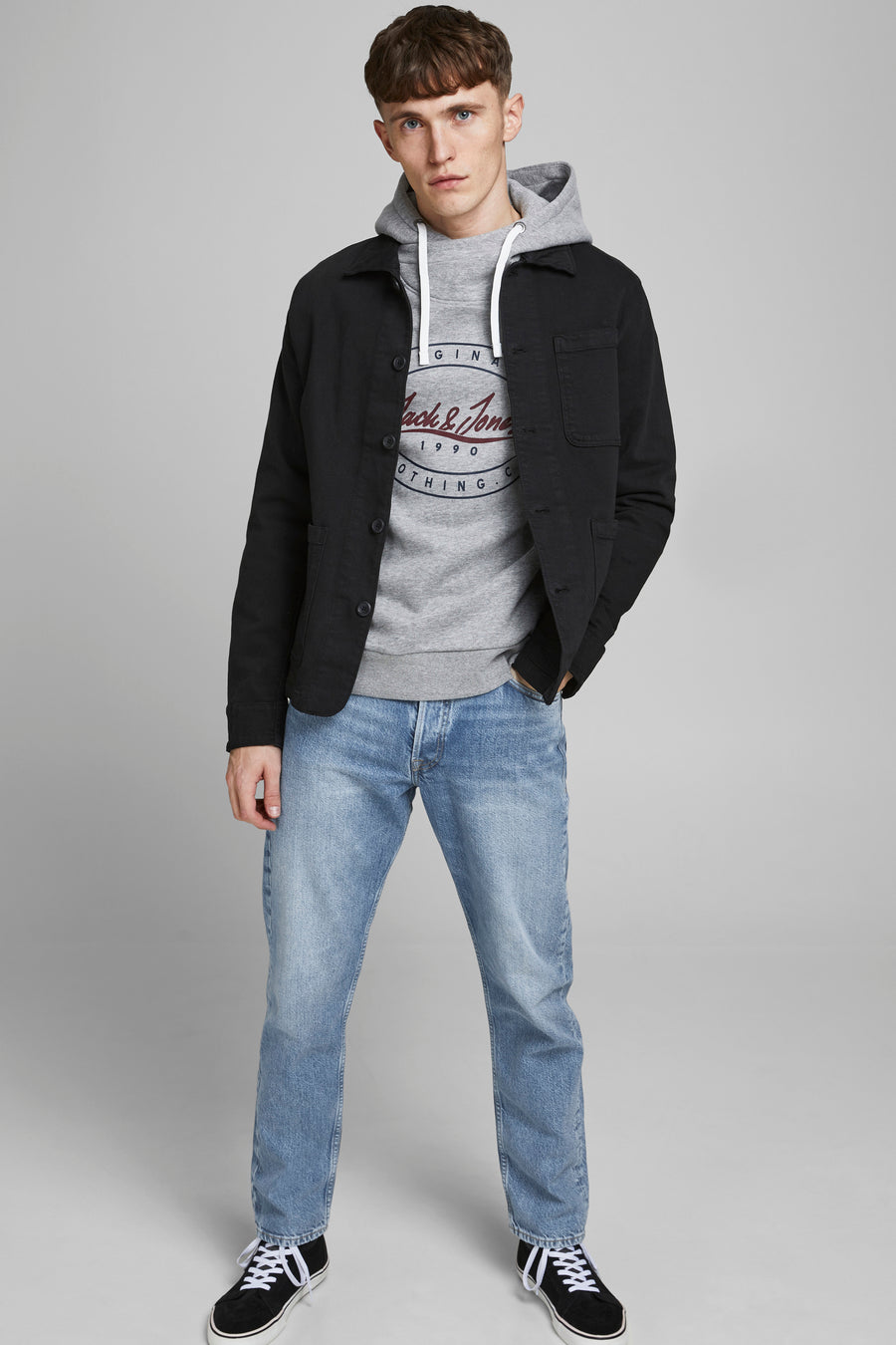 Jean fuselé bleu clair de JACK & JONES JEANS INTELLIGENCE, porté avec un sweat gris, une veste noire et des baskets.