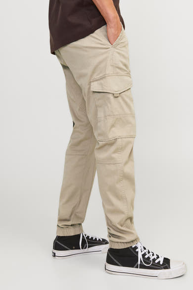 Pantalon cargo beige de JACK & JONES JEANS INTELLIGENCE avec poches latérales et baskets noires.