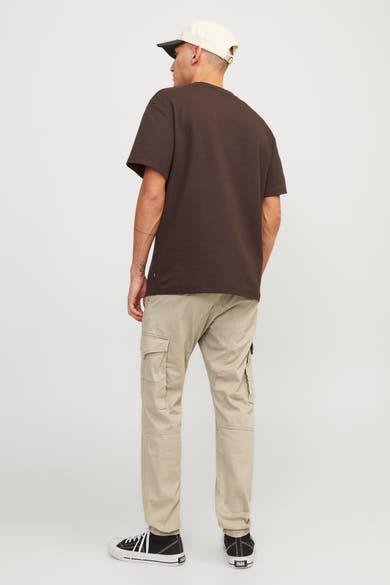 Pantalon cargo beige de JACK & JONES, avec des poches cargo et des chaussures noires et blanches.
