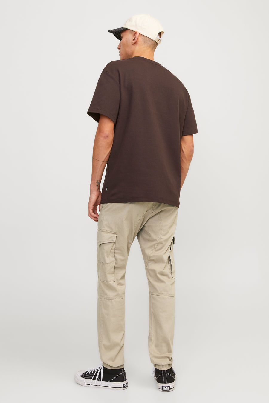 Pantalon cargo beige de JACK & JONES, avec des poches cargo et des chaussures noires et blanches.
